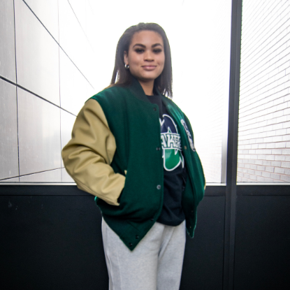 Student wearing green varsity jacket with the Nipissing University crest