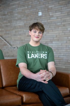 Student wearing a green tee with the Nipissing Lakers logo across the front