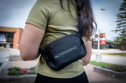 Student wearing a belt bag on her back with the Nipissing alumni logo on the front.