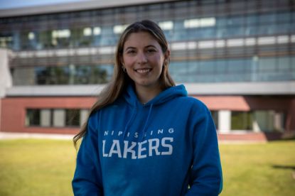 Student wearing a sapphire Lakers Hoodie with "Nipissing Lakers" on the front