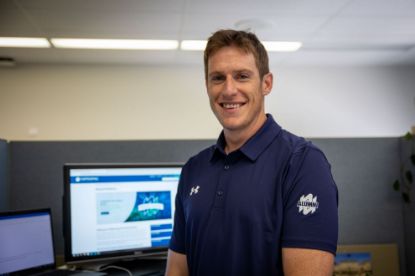 Man wearing a Navy Alumni Golf Polo with the "Alumni " logo on the arm