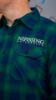 Man wearing a blue/green flannel shirt with the "Nipissing University" logo on the front